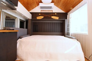 Una stanza con un letto, soffitto in legno e condizionatore d'aria a parete.
