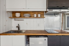 A compact kitchen with a wooden countertop, stainless steel sink, and a Kenmore refrigerator.