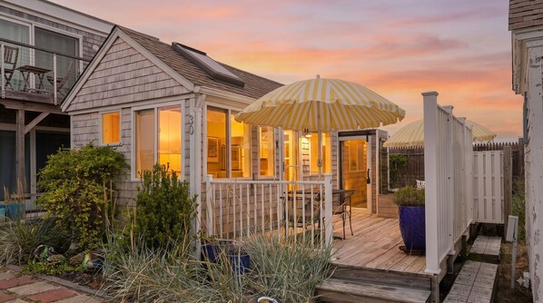 Una casa con terraza, mobiliario exterior y un patio cubierto.