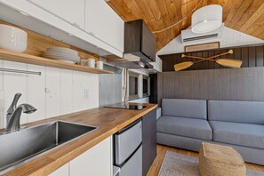 A compact kitchen with a built-in stove, a sink, and a compact refrigerator.