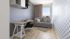 A modern living room with a grey sofa, a wooden desk, and a white shelving unit. - Elite Apartments Seastory (Gdansk)