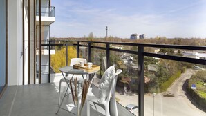 A balcony with a table and chairs, overlooking a road and buildings. - Elite Apartments Seastory (Gdansk)