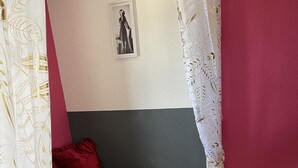 Una habitación con una cama, un cuadro en la pared y una cortina.