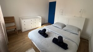 A bedroom with a bed, a dresser, a chair, and a blue door. - Appartement T3 vue mer (Toulon)