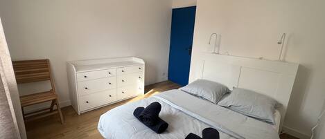 A bedroom with a bed, a dresser, a chair, and a blue door.