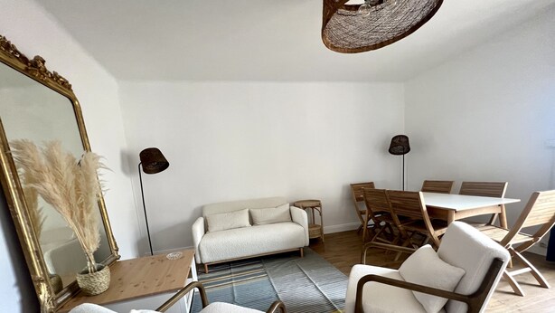 A modern living room with a sofa, armchairs, a dining table, and a large mirror. - Appartement T3 vue mer (Toulon)