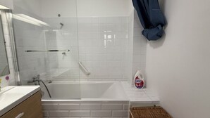 A bathroom with a glass-enclosed shower, a white bathtub, a sink with a mirror, and a bottle of liquid soap on the counter. - Appartement T3 vue mer (Toulon)