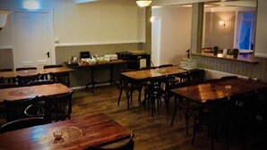 Een restaurant met houten tafels en stoelen, een balie en uitzicht op de straat.