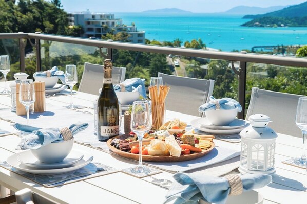 A table set for a meal with a bottle of wine, glasses, and a variety of food items.