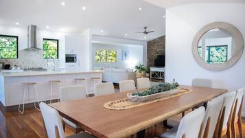 A modern kitchen with white cabinetry, a wooden dining table, and bar stools.