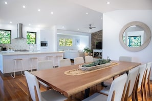 A modern kitchen with white cabinetry, a wooden dining table, and bar stools.