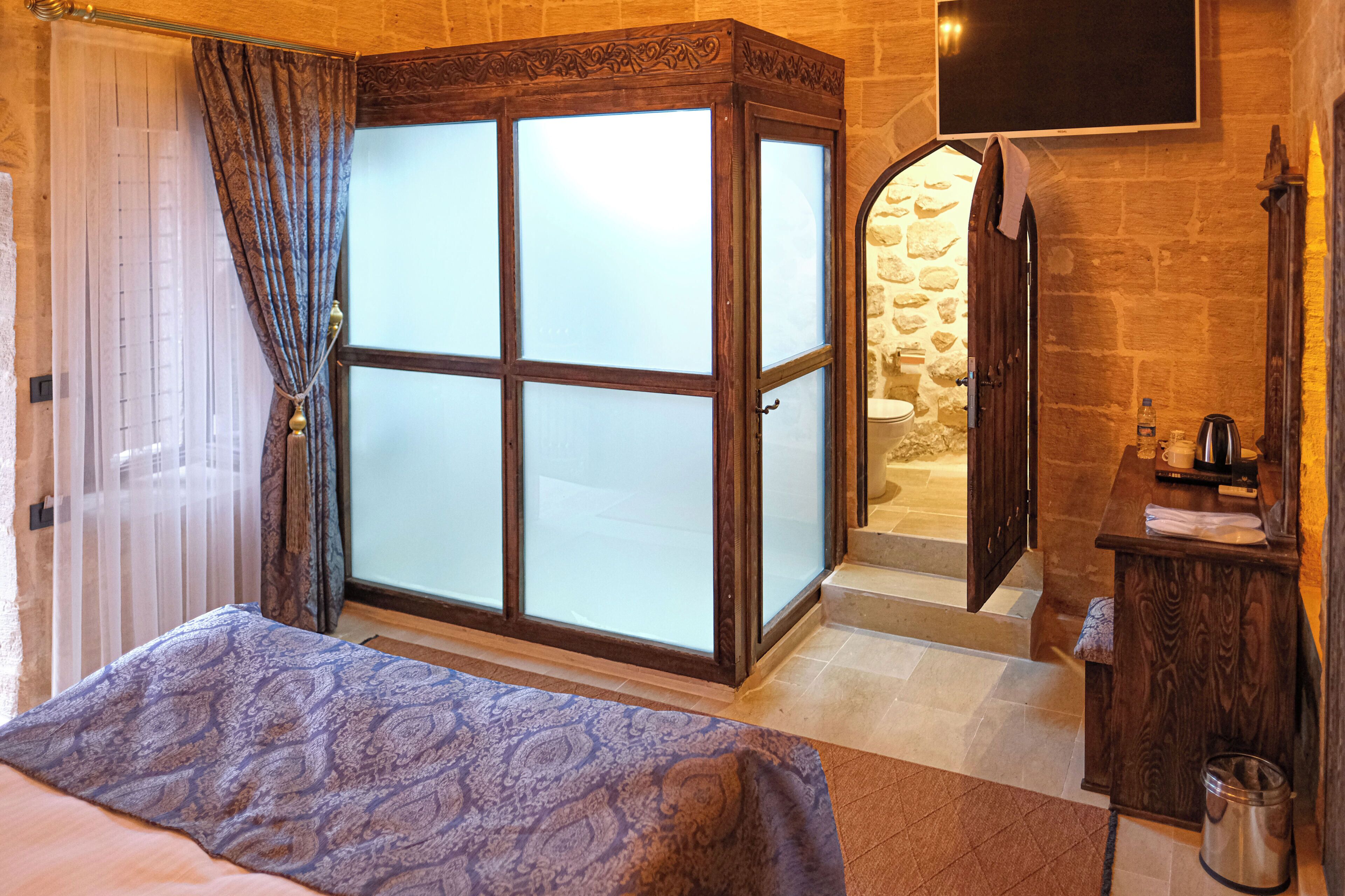 A hotel room with a bed, a wardrobe, a mirror, and a bathroom visible through an open door.