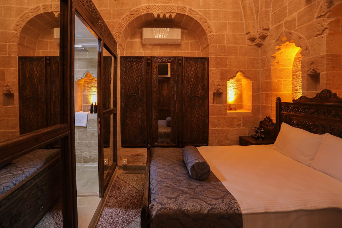 A room with a bed, wooden furniture, and stone walls.