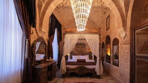 Un dormitorio con cama con dosel, candelabro y paredes de piedra.