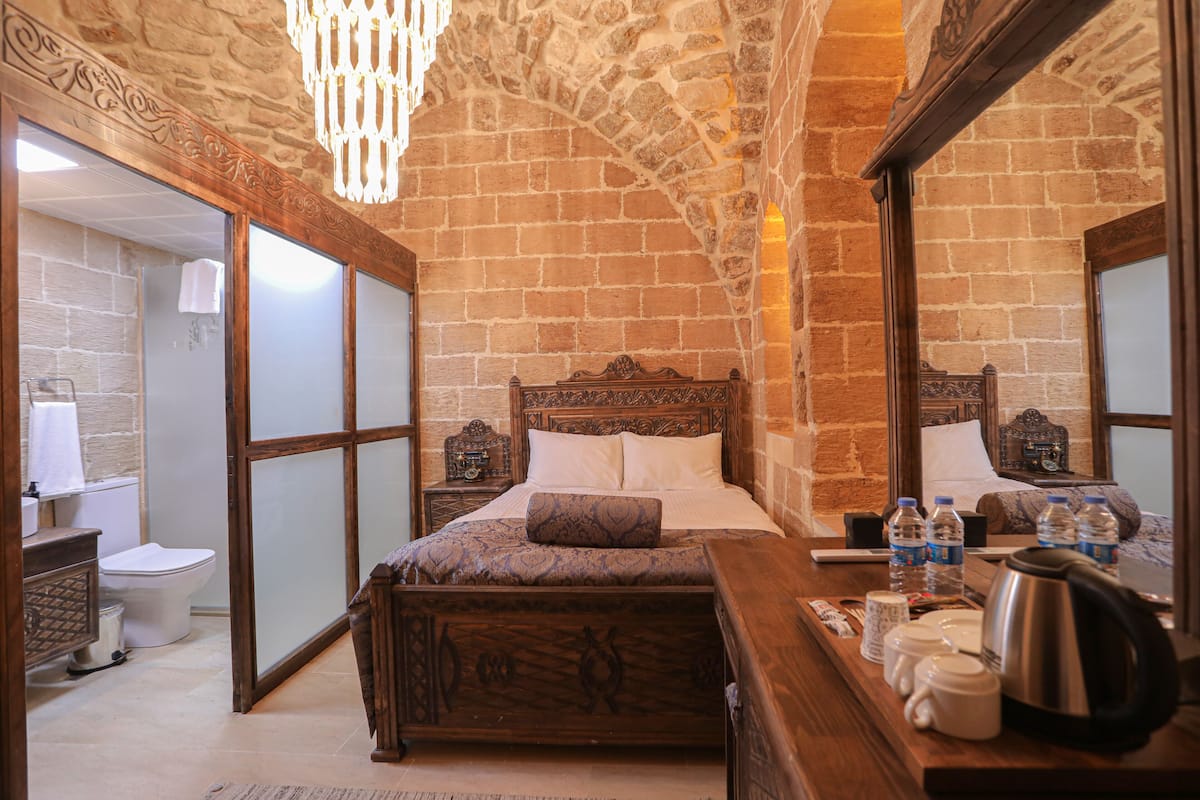 A bedroom with a wooden bed, a nightstand, a mirror, and a dresser.