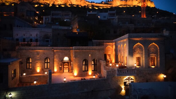Un edificio histórico con ventanas de arco y un patio, iluminado con cálida luz.