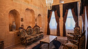 Una habitación con pared de piedra, muebles ornamentales y una araña.