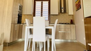 Une cuisine moderne avec des poutres en bois, des armoires blanches, une table à manger avec des chaises et un réfrigérateur.