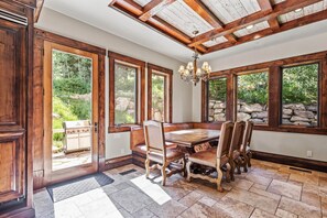Una cocina amplia con un gran comedor de madera, armarios empotrados y ventanas grandes con vistas a un jardín.
