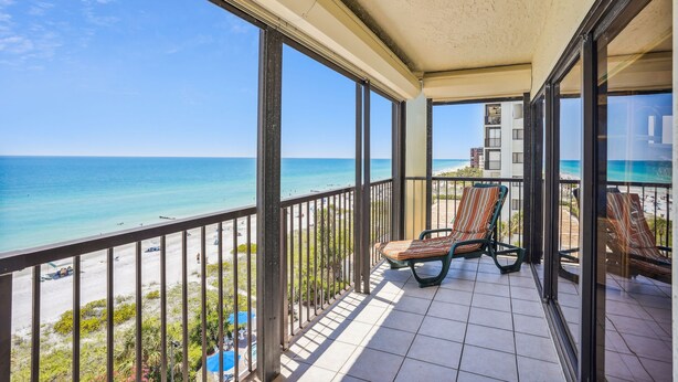 Een balkon met uitzicht op strand en zee.