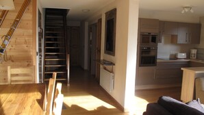 Een moderne keuken met roestvrijstalen apparatuur, een houten trap en een gezellige zithoek.