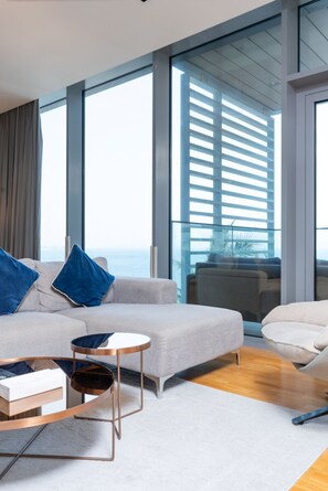 Una sala de estar moderna con un sofá, una mesa de centro y vistas amplias a través de ventanas grandes.