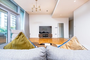Uma sala de estar moderna com um sofá, televisão e piso de madeira.