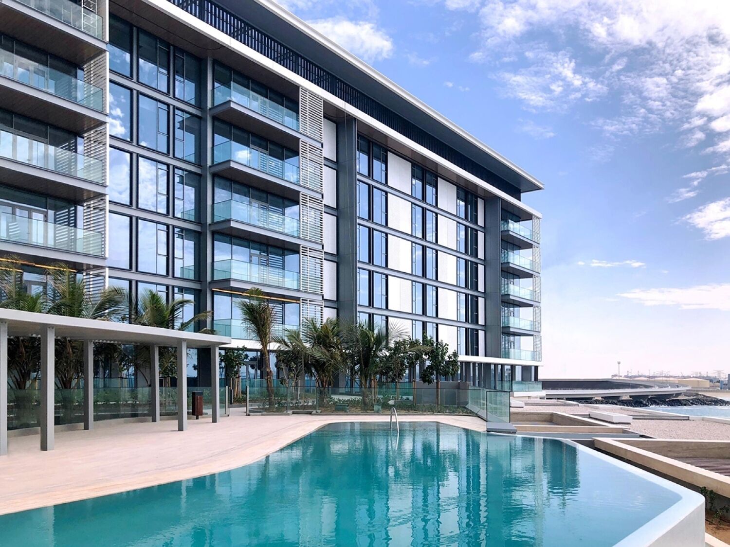 A modern building with a swimming pool, large windows, and balconies.