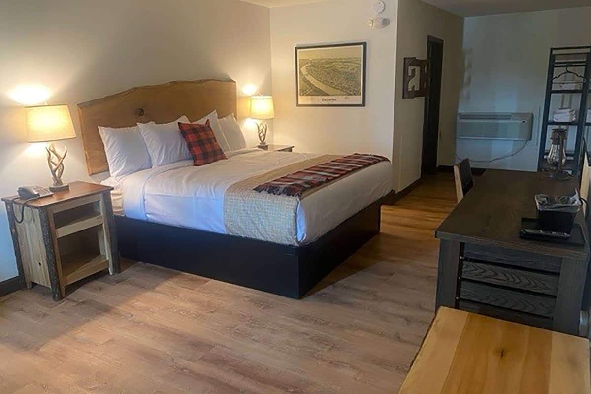 Une chambre à coucher comprenant un lit, des tables de chevet, un bureau et un appareil de climatisation.