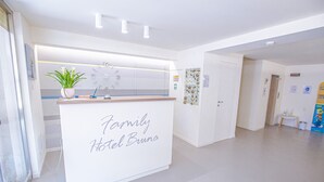 Ein Empfangsschalter mit einem Schild, auf dem 'Family Hotel Bruno' steht, und einer Topfpflanze darauf.