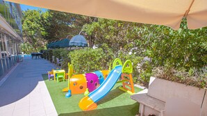 Ein Kinderspielbereich mit Rutsche, Sitzgelegenheiten und einer überdachten Bank.