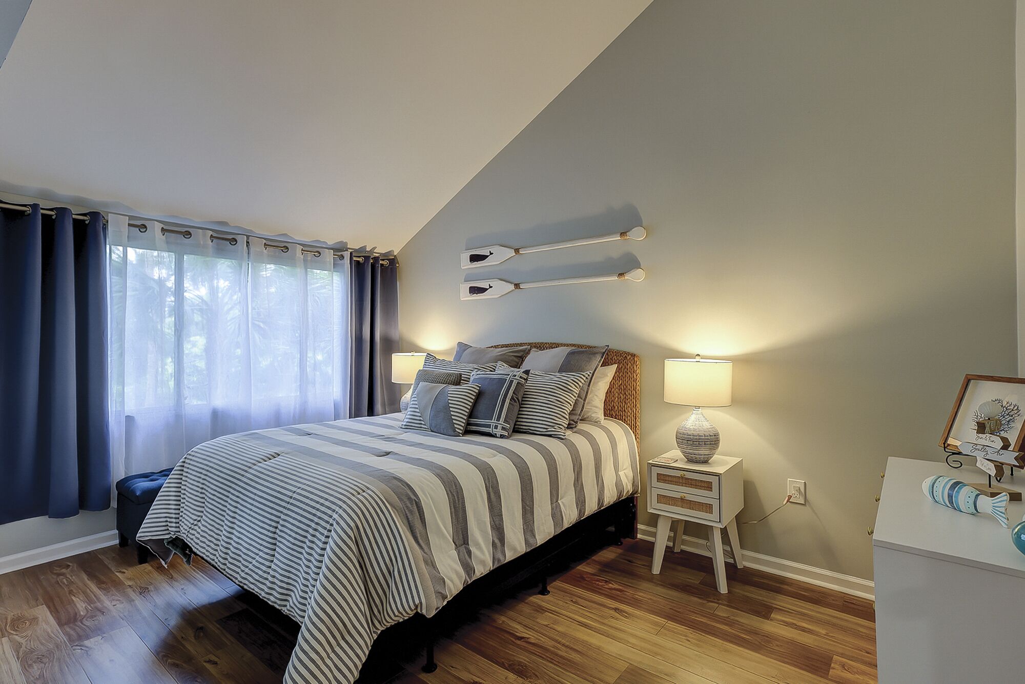 A bedroom with a bed, bedside tables, and a window with curtains.