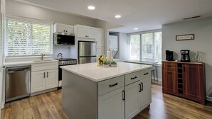 A modern kitchen with white cabinets, stainless steel appliances, and a central island. - Sunset Rentals | Treetops 6104 (Hilton Head Island)