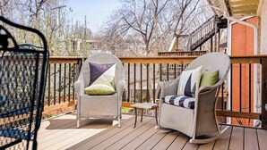 A wooden deck with wicker rocking chairs and a small table. - Chic Victorian Manor | Sleeps 12 | Congress Park (Denver)