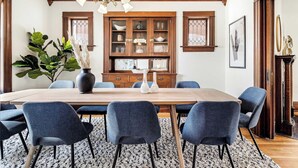 A dining room with a wooden table, six chairs, a chandelier, and a cabinet with glass doors. - Chic Victorian Manor | Sleeps 12 | Congress Park (Denver)