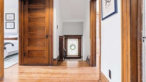 A wooden hallway with a door, a stained glass window, and a framed picture on the wall. - Chic Victorian Manor | Sleeps 12 | Congress Park (Denver)