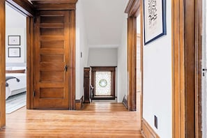 A wooden hallway with a door, a stained glass window, and a framed picture on the wall.