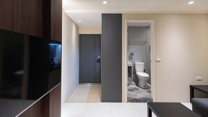Un salon moderne avec un téléviseur à écran plat, un meuble en bois foncé et un mur d’accent de couleur grise.