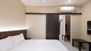 Une chambre d’hôtel avec un grand lit, un bureau, une chaise, une télévision et un appareil de climatisation.