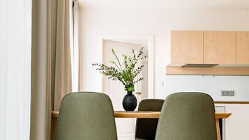 Ein zeitgemäßer Essbereich mit zwei grünen Stühlen, einem Holztisch und einer Stehlampe.