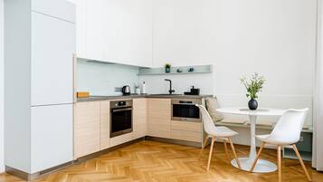 Een moderne keuken met lichte houten kastjes, roestvrijstalen apparatuur en een visgraatparketvloer.