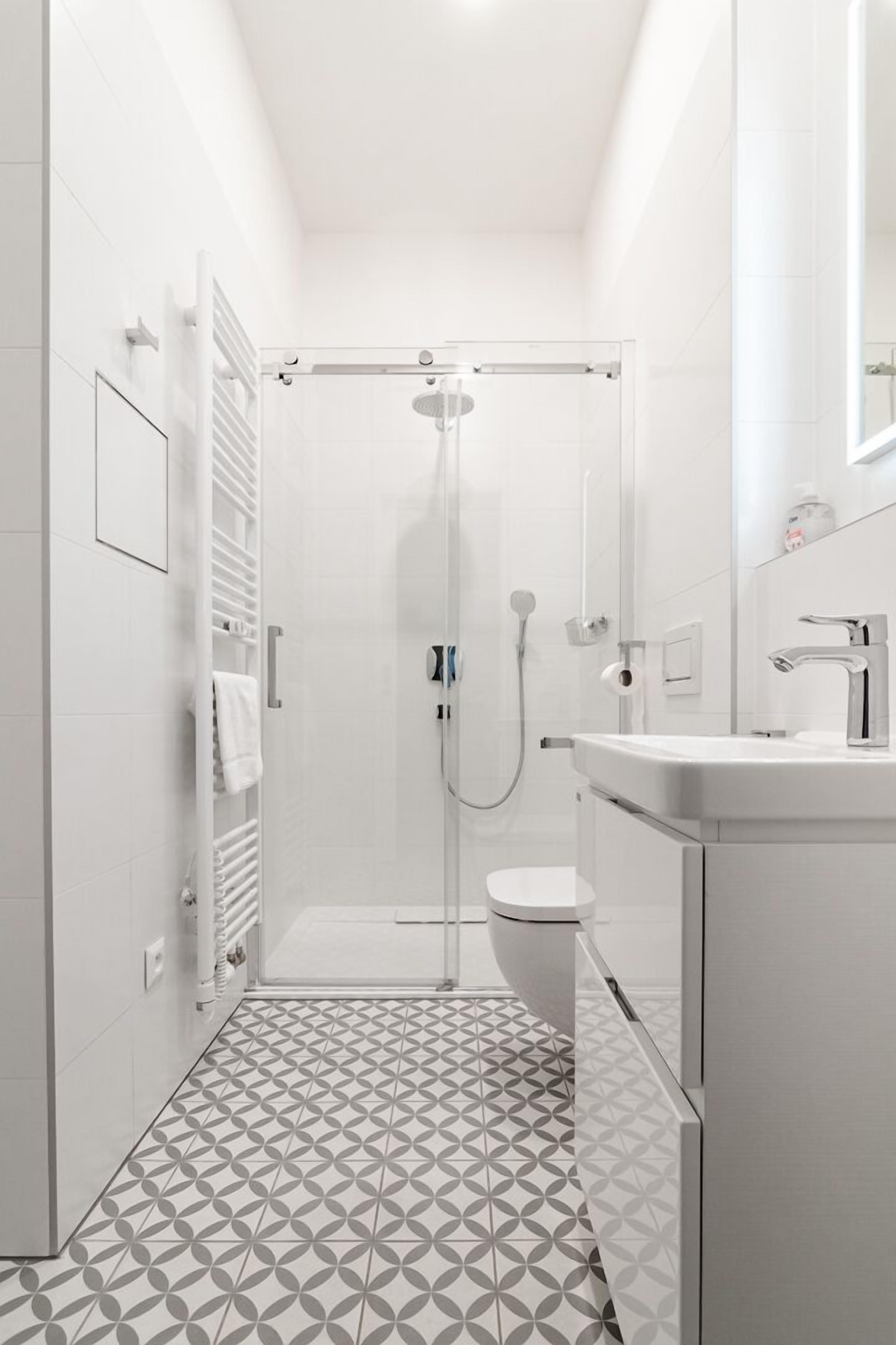 A modern bathroom with a shower, toilet, and sink.