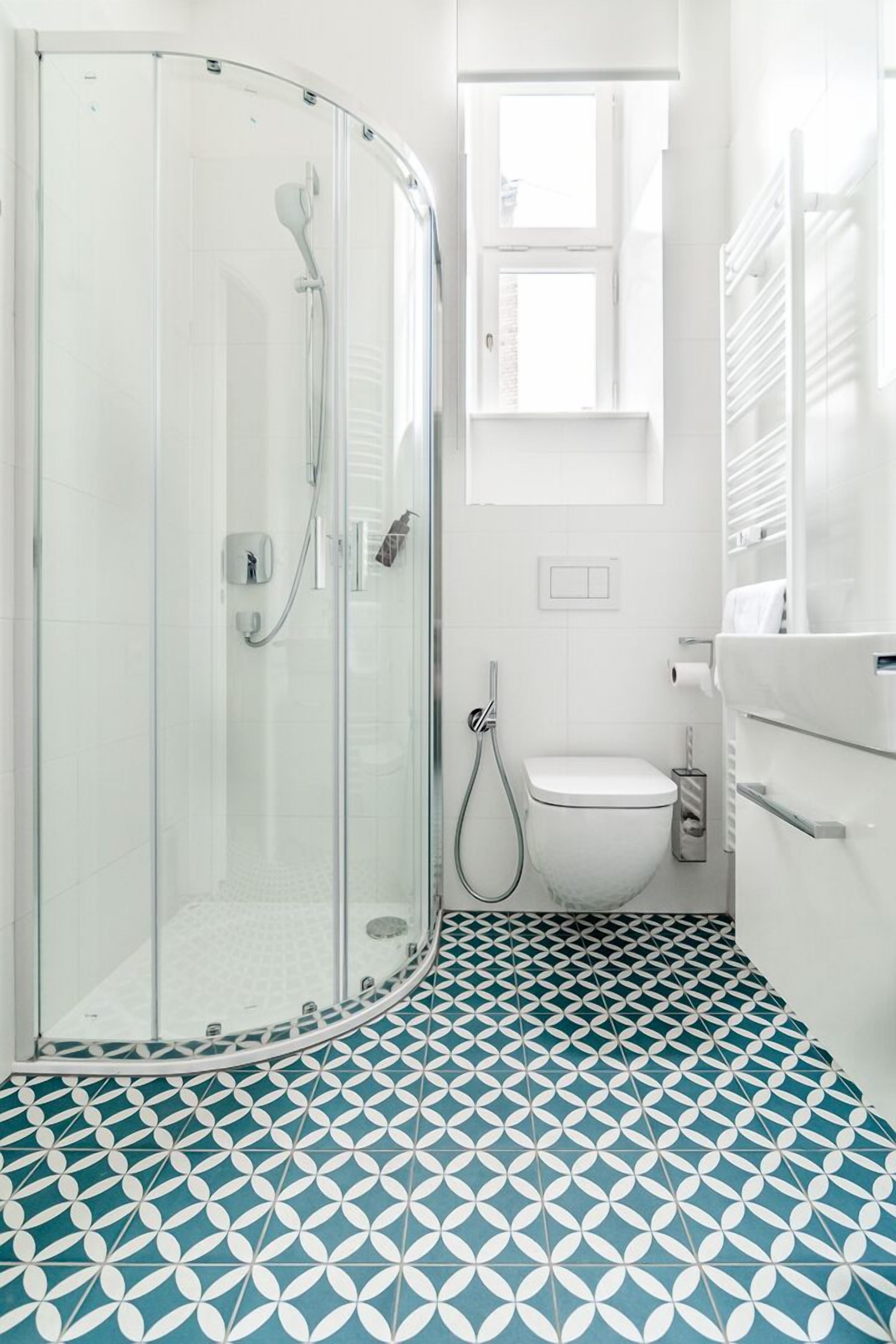 Een badkamer met een douchecabine van glas, een toilet en een wastafel.