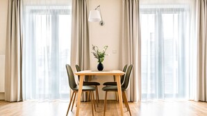 A dining area with a wooden table, four chairs, and a vase with flowers. - Apartment BRNO (Brno)