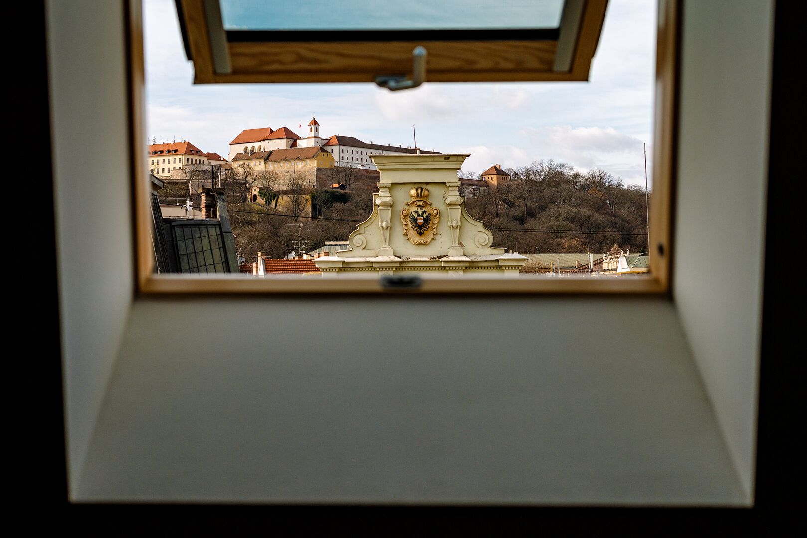 Une vue à travers un puits de lumière d’un bâtiment dont l’architecture remarquable est ornée d’un blason.
