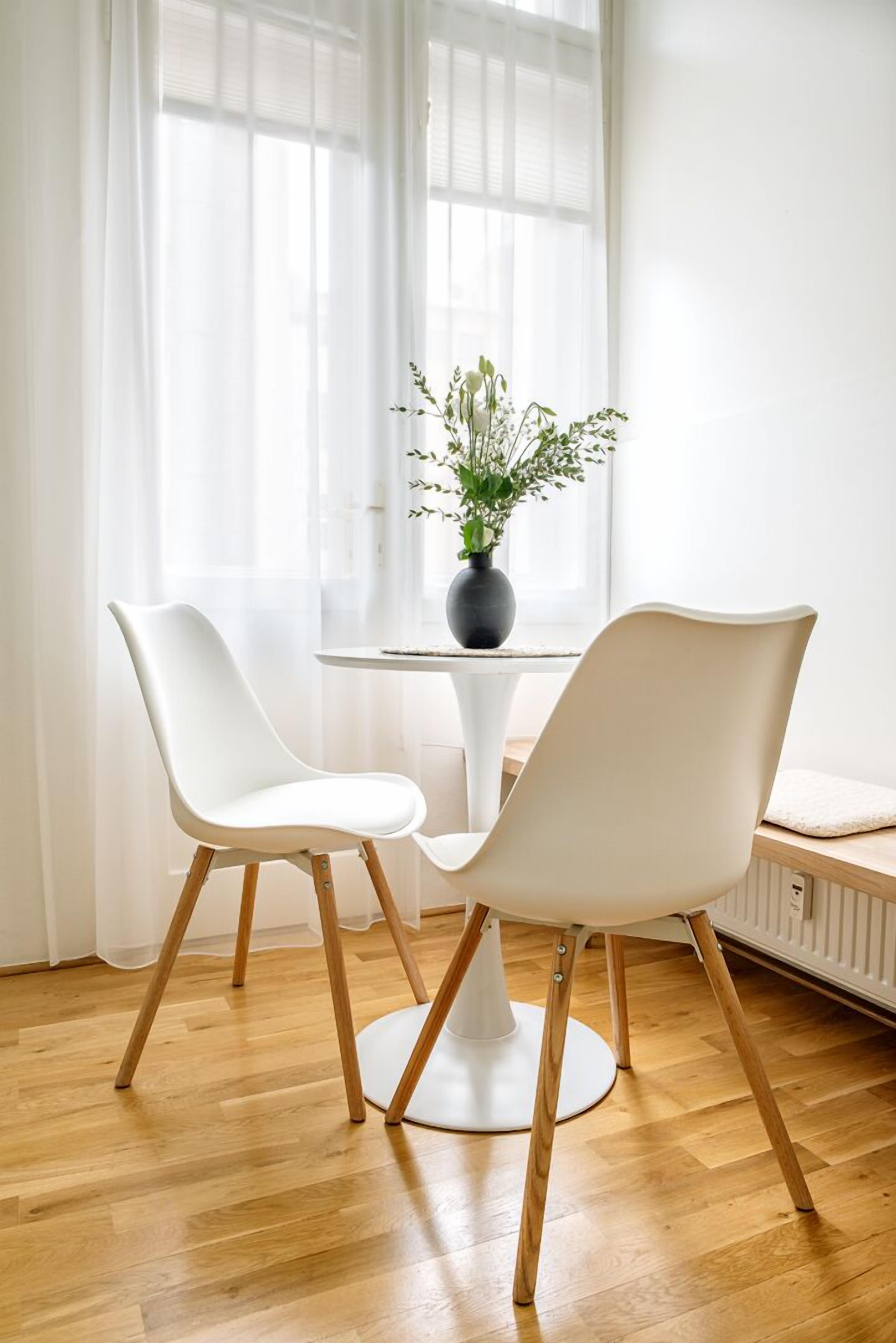 A modern room with two white chairs, a small table, and a potted plant.
