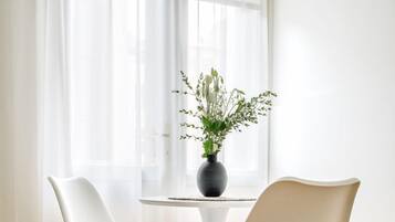 A modern room with two white chairs, a small table, and a potted plant.