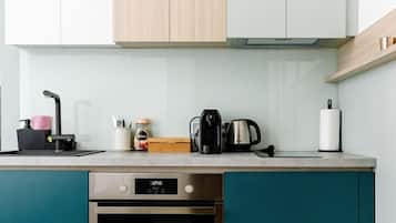 Eine moderne Küche mit türkis-blauen Schränken, einem Edelstahlbackofen und einer Kaffeemaschine auf der Arbeitsfläche.