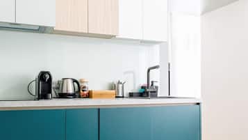 Una cocina moderna con armarios color aguamarina, encimera de madera y hervidor de acero inoxidable.
