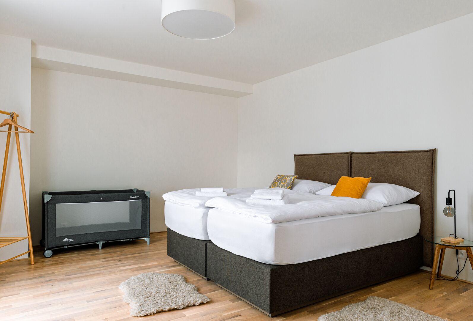 A modern bedroom with a large bed, a TV on a stand, and a small side table.
